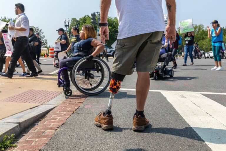 Advocates, some using wheelchairs and one with a flame patterned prosthetic leg, march during NCIL's annual March and Rally.