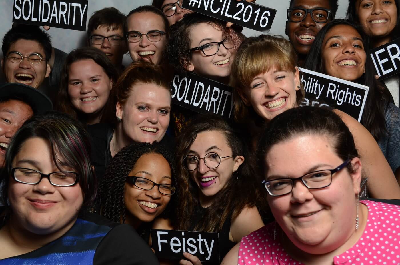A group of young advocates hold up signs that say "Feisty" "Solidarity" and "#NCIL2016".