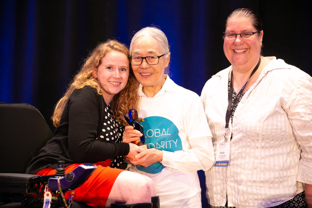 Stephanie Woodward poses with Yoshiko Dart and Sarah Launderville holding an award.