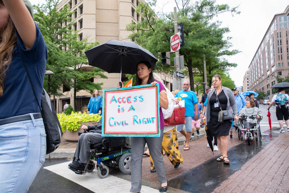 An advocate carries a sign that says "access is a civil right".