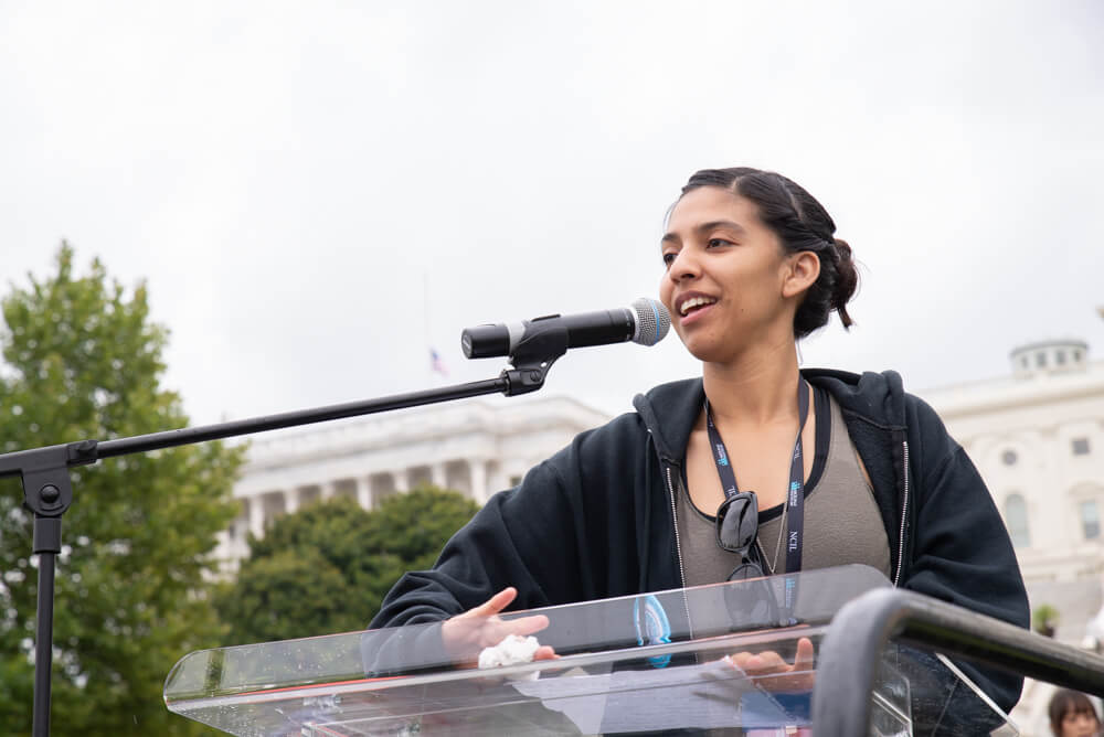 Jessica Jimenez speaks into a microphone at NCIL's annual rally.