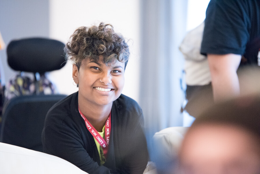 An young advocate with light brown skin and short curly brown hair smiles at the camera.