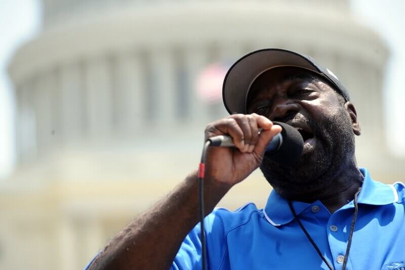 Stan Holbrook speaks into the microphone with the U.S. Capitol Rotunda in the background.