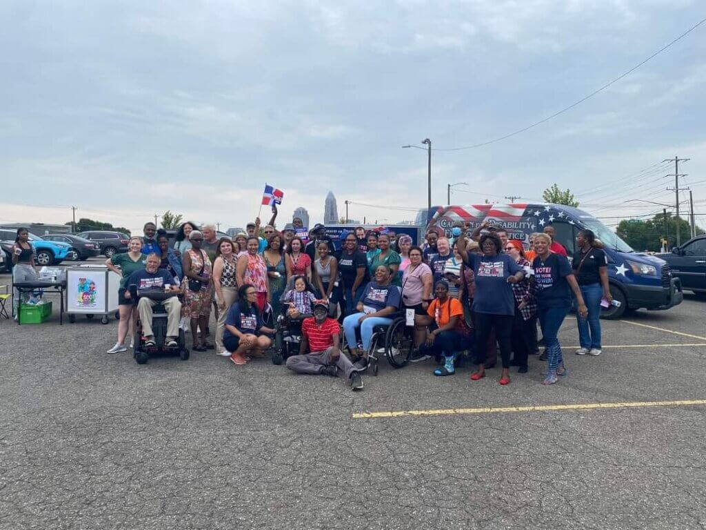 Approximately 40 people gather in front of the Caravan vehicle for a group photo in Charlotte, North Carolina.
