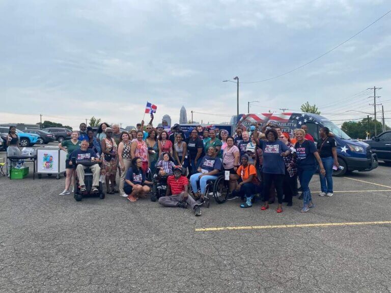 Approximately 40 people gather in front of the Caravan vehicle for a group photo in Charlotte, North Carolina.