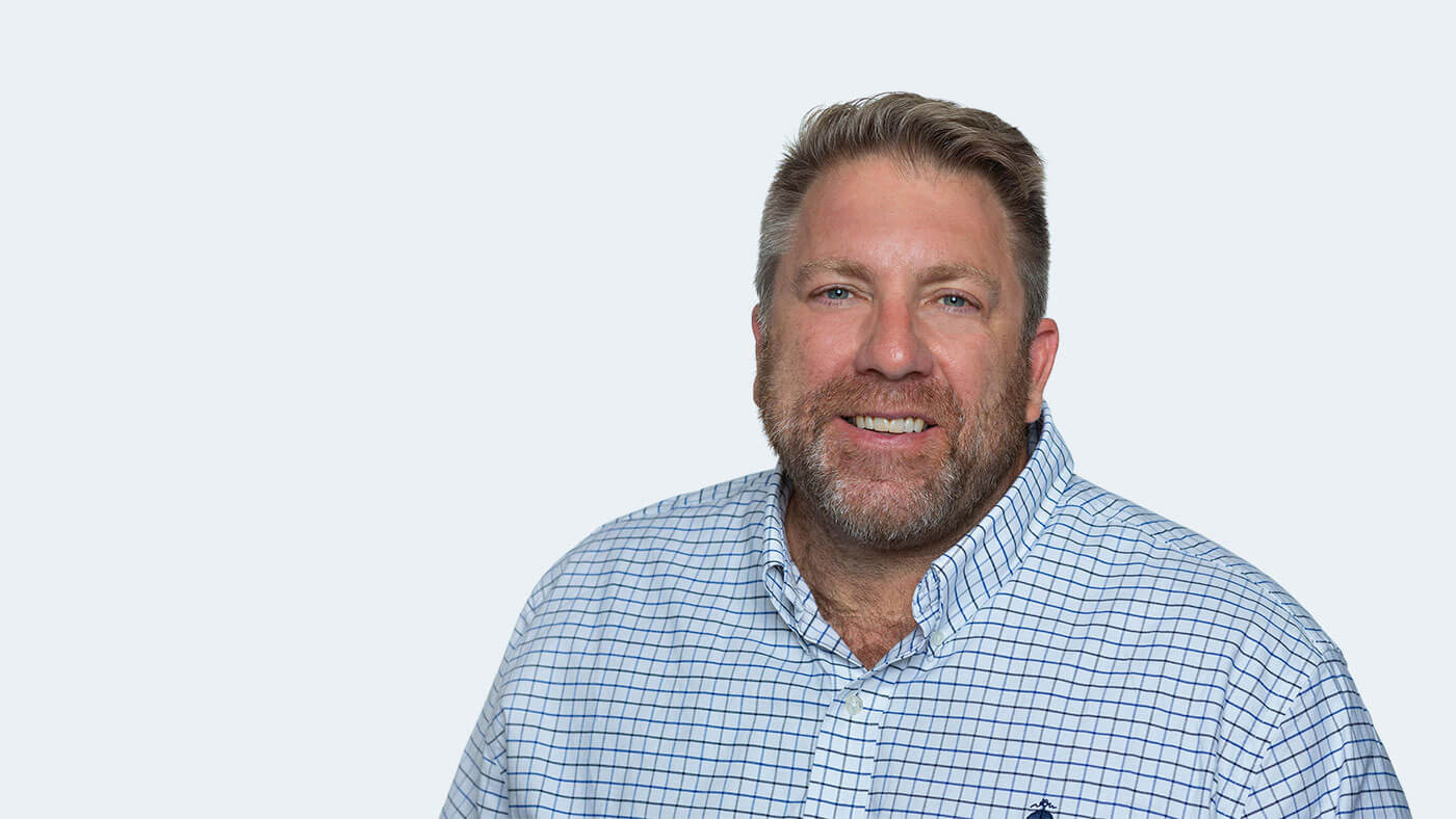 Bradley Rightnowar, a white person with short, dark blonde hair and scruffy facial hair, smiles at the camera.