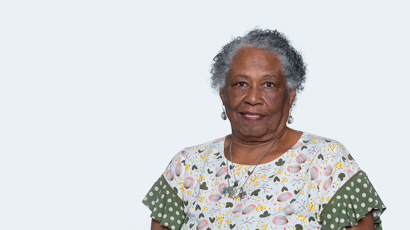 Carolyn Mason Burton, an older Black woman with short curly grey hair, smiles at the camera.