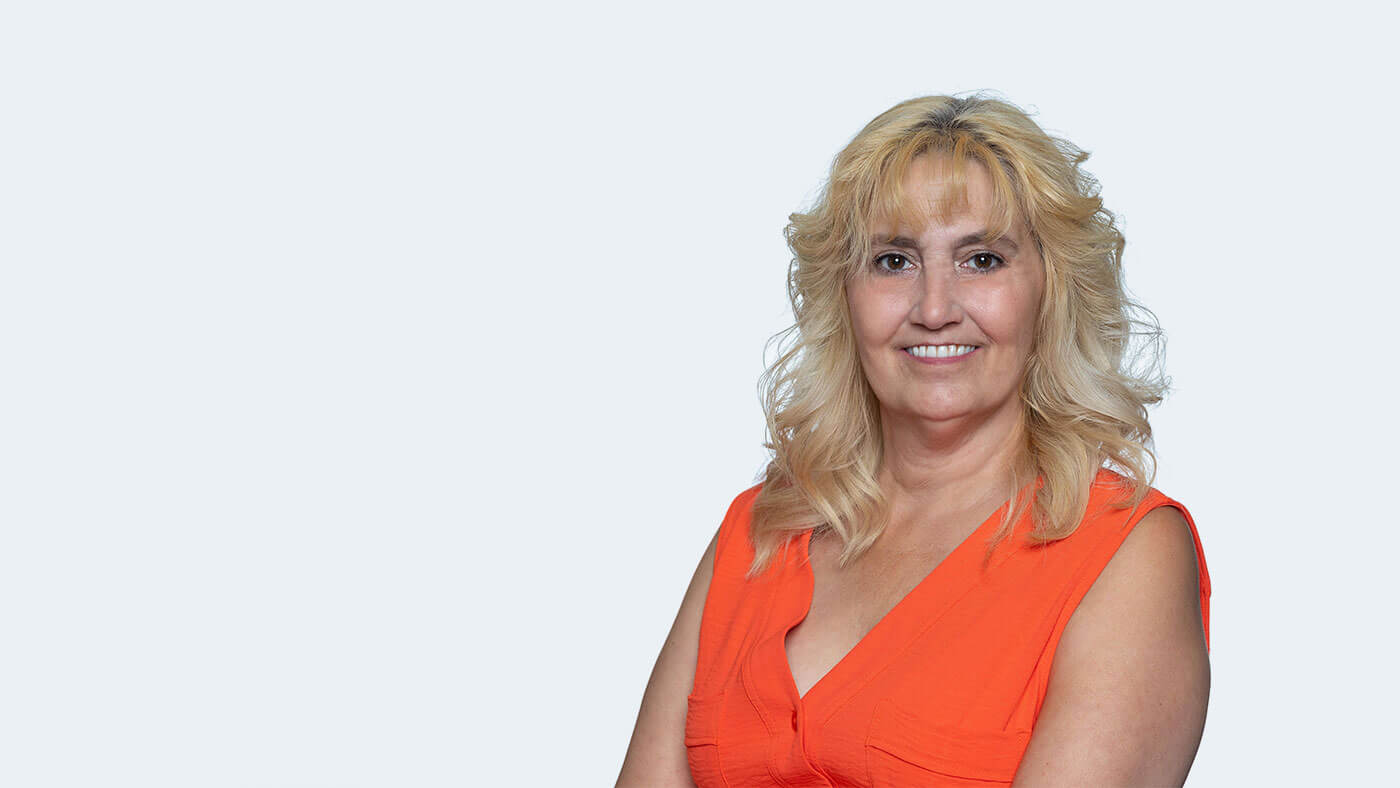 Cristina Welch, a white person with wavy shoulder length blonde hair, smiles at the camera.