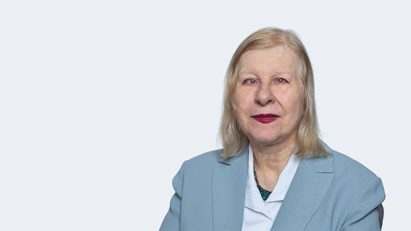 Doris Ray, a white woman with shoulder length blonde hair and dark red lipstick, smiles at the camera.