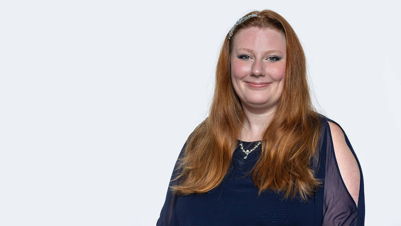 Emily Smith, a white woman with medium length red hair with a sparkly hair clip, smiles at the camera.