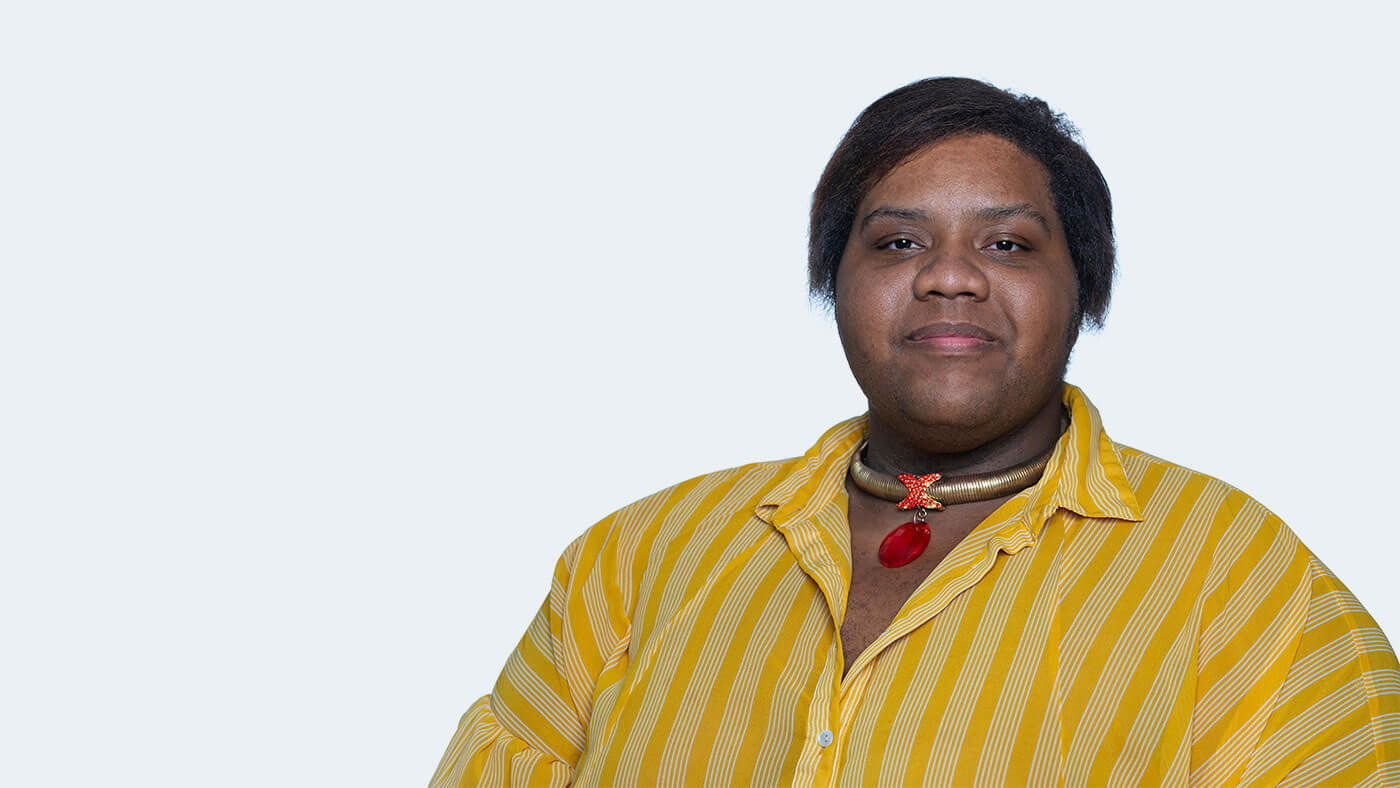 Jakeel Abdullah, a Black person with short black hair, smiles at the camera.