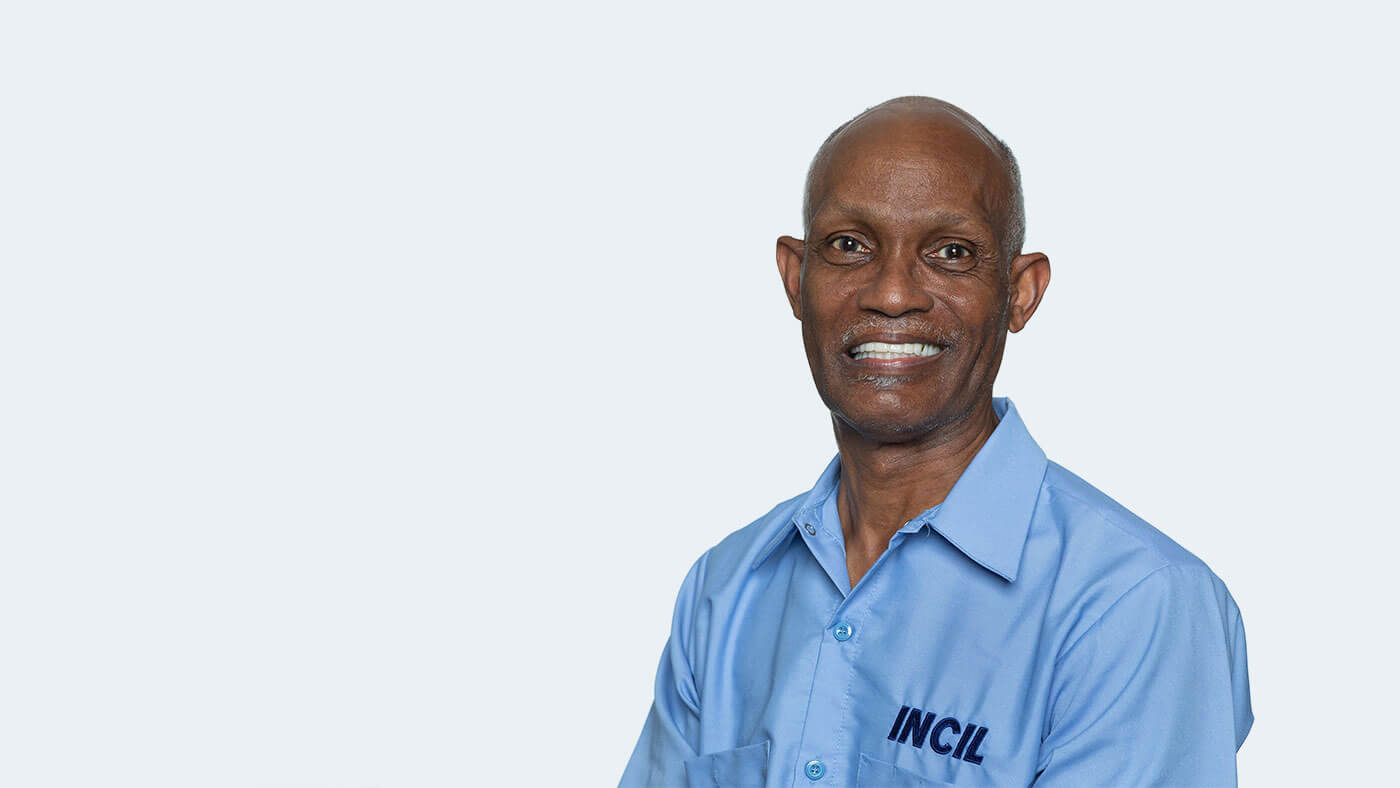 John Herring, a Black bald person wearing an INCIL polo shirt, smiles at the camera.