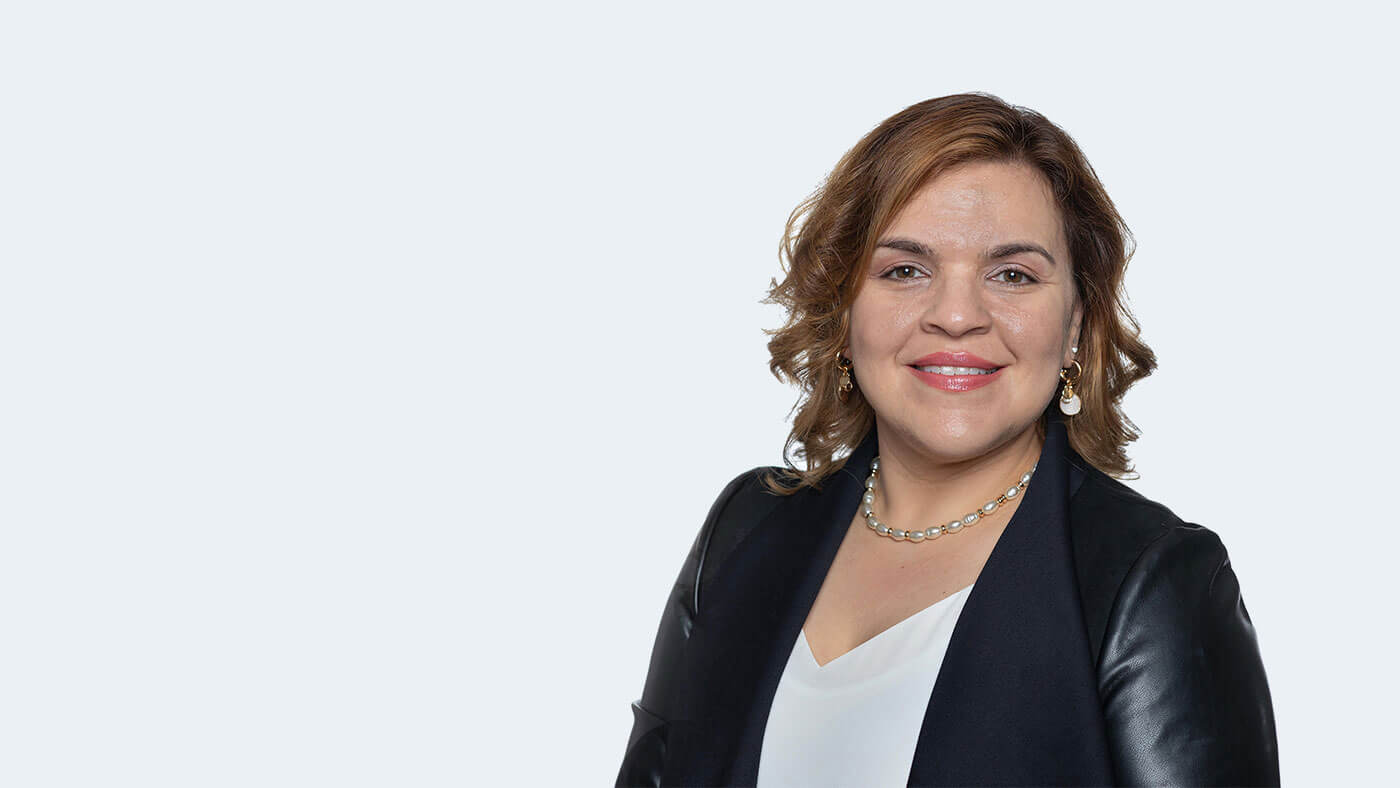 Lynette McRae, a person with shoulder length wavy brownish-blonde hair, smiles at the camera.