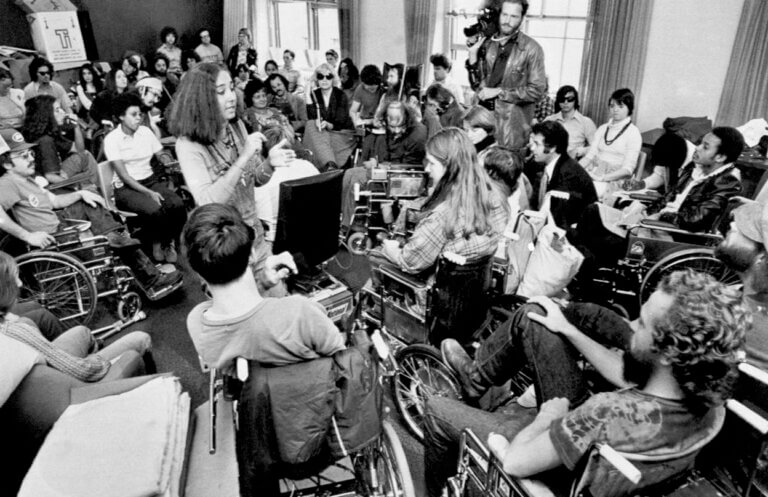 Lynette Taylor provides American Sign Language interpretation while surrounded by approximately 60 disabled protesters and a camera man. Image credit: AP Images.