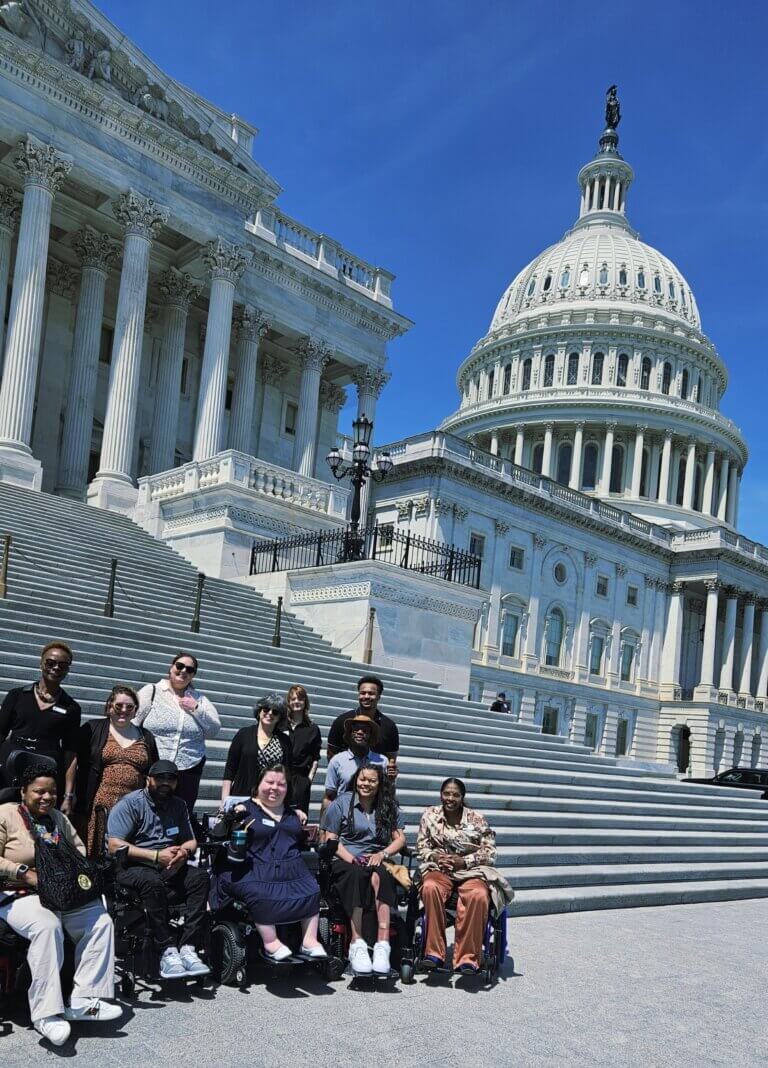 Eleven people from Independence Now in Silver Springs, Maryland gather together for a group photo with the U.S. Capitol behind them during a Congressional visit.
