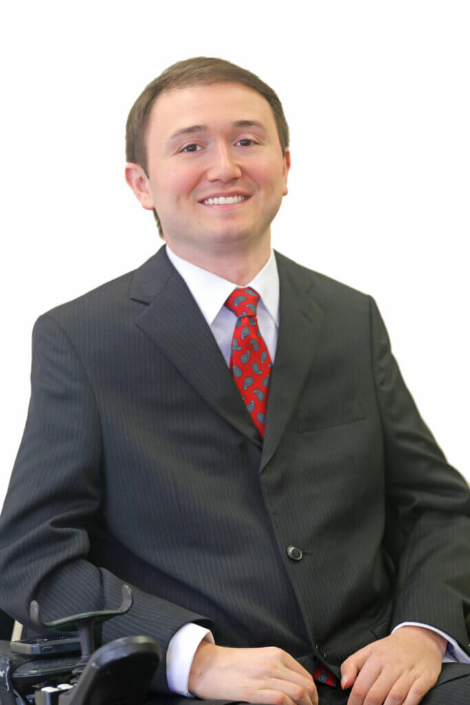 white male with short dark hair sits in his power wheelchair