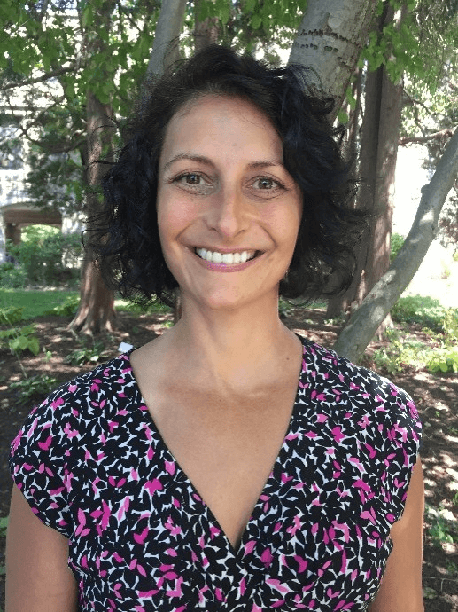 A headshot of woman in front of a tree, smiling