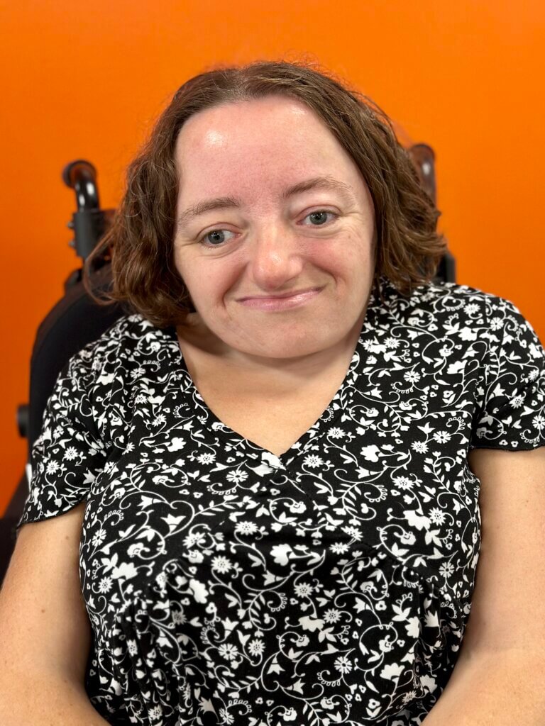 A white woman with shoulder length dark blond hair in a power wheelchair.