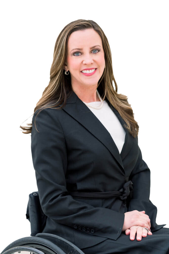 white female with long dark hair wearing a black suit sits in her wheelchair