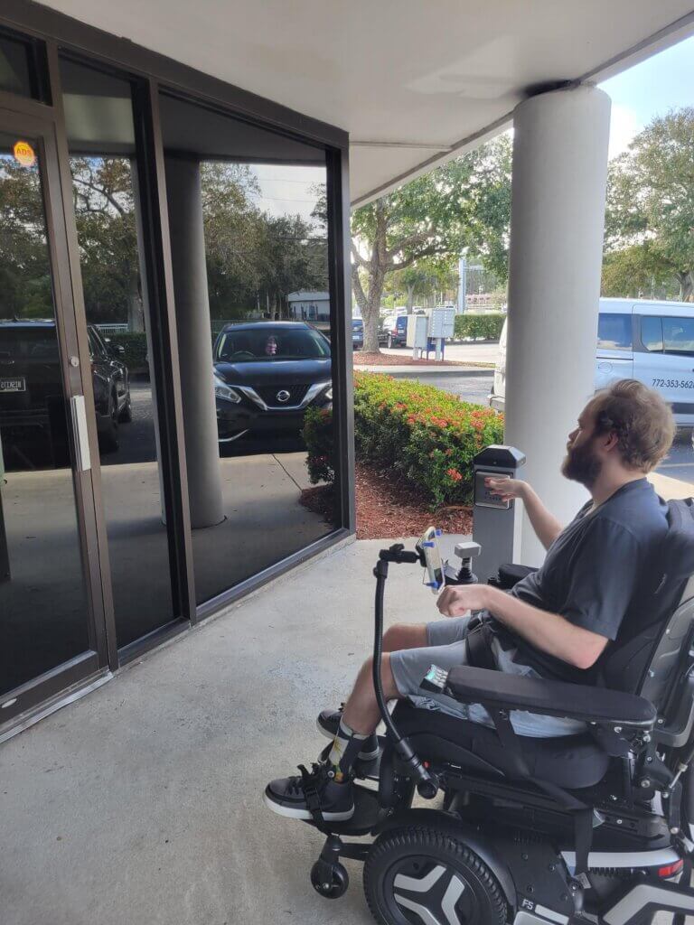A person using a power chair approaches a door with a new automatic door opener.
