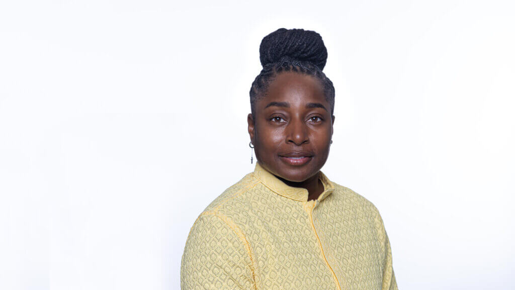 Headshot of Nasira Johnson. Nasira has braided hair styled in a high bun wears a textured light-yellow jacket and is posed against a plain white background.