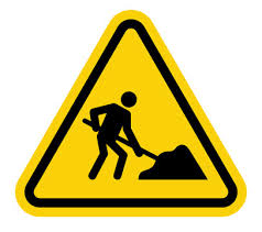Yellow triangular road sign showing the symbol for construction - a stick figure digging.